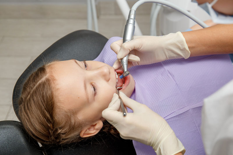 Child girl having professional dental cleaning in dentist office