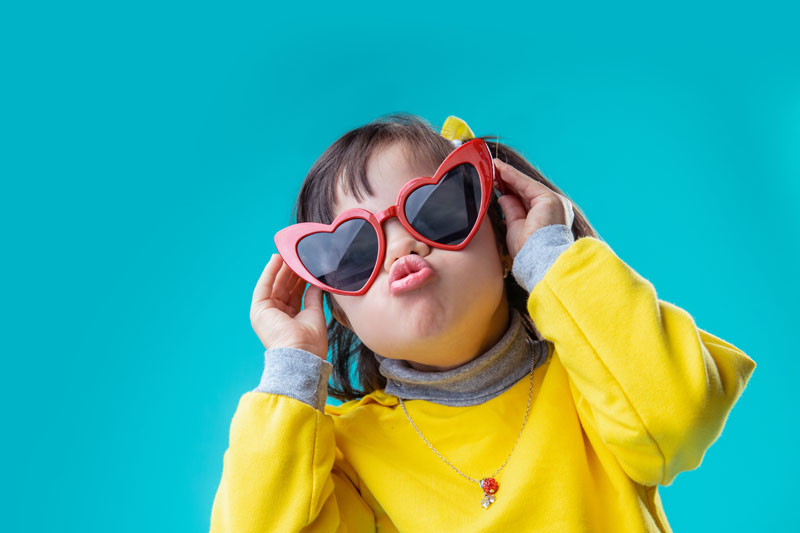 Positive interested girl wearing weird big glasses in form of heart