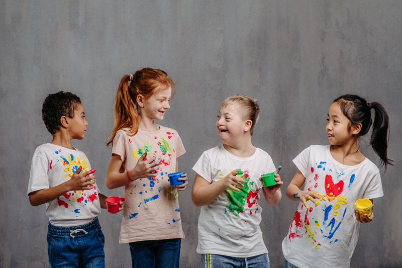 Portrait of happy kids with finger colours and painted t-shirts, studio shoot.